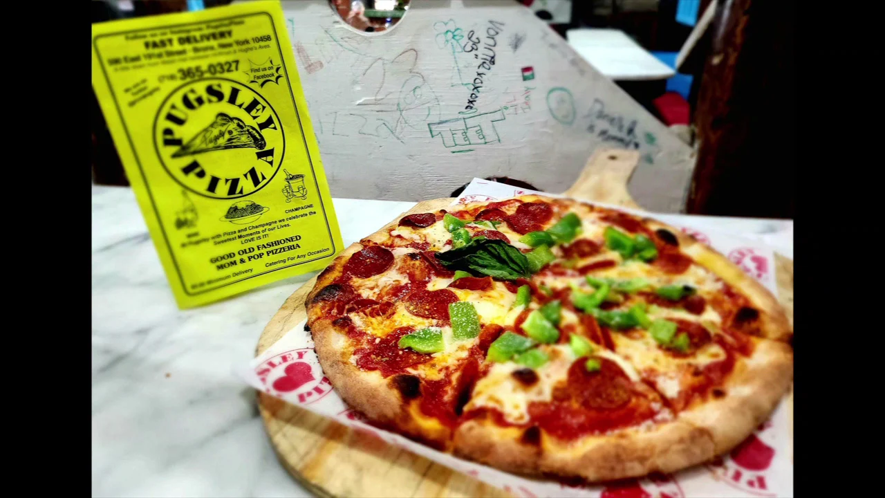 Pugsley Pizza featured image Close-up of a pepperoni pizza on a wooden board with a Pugsley Pizza flyer, Belmont Bronx.