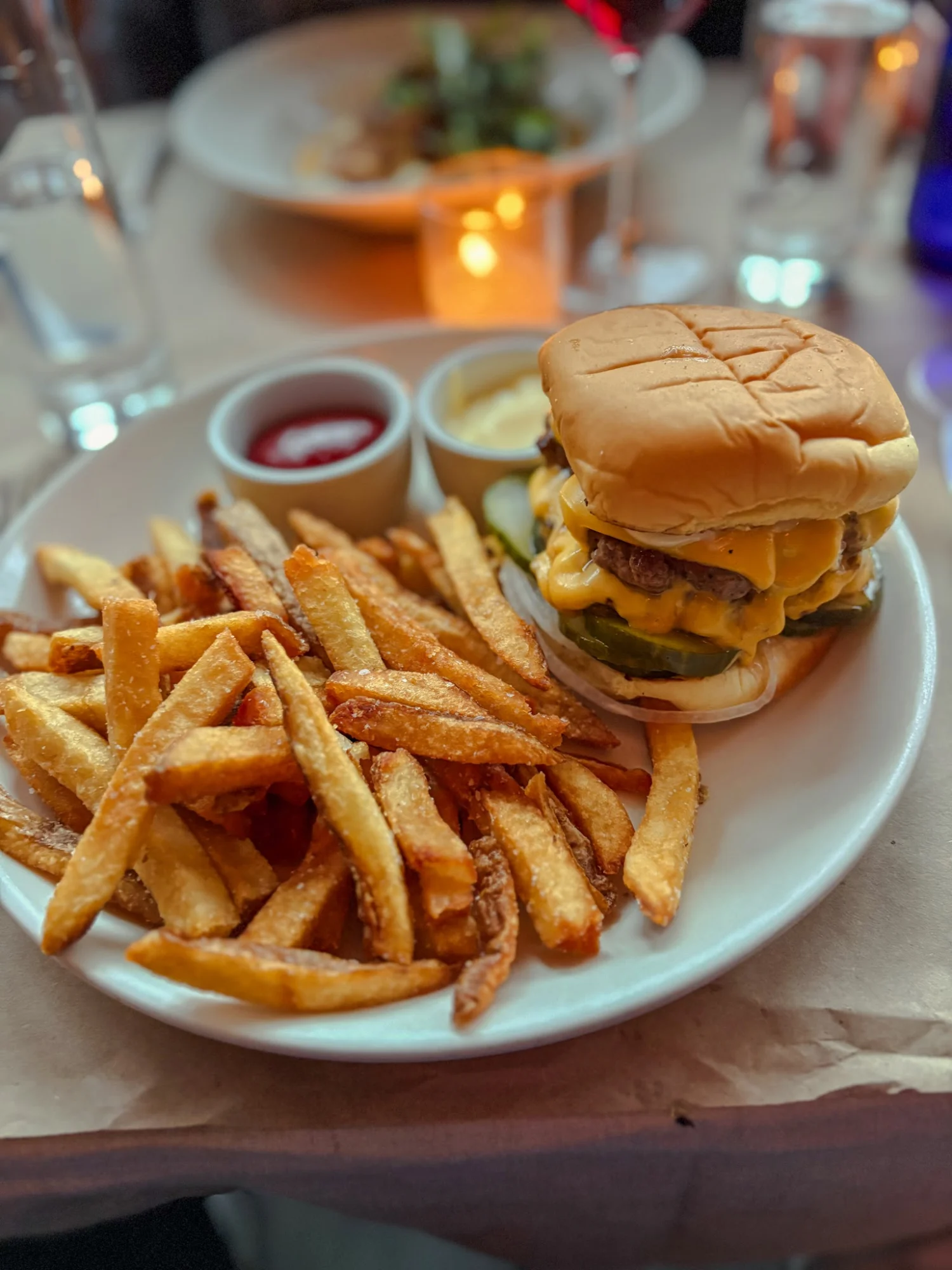 Plate of burger and fries on a table at Ingas Bar, Brooklyn Heights.