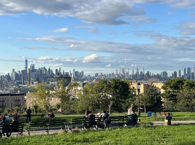 View of the Manhattan skyline from Sunset Park with benches and people in the foreground, Sunset Park, Bronx NYC.