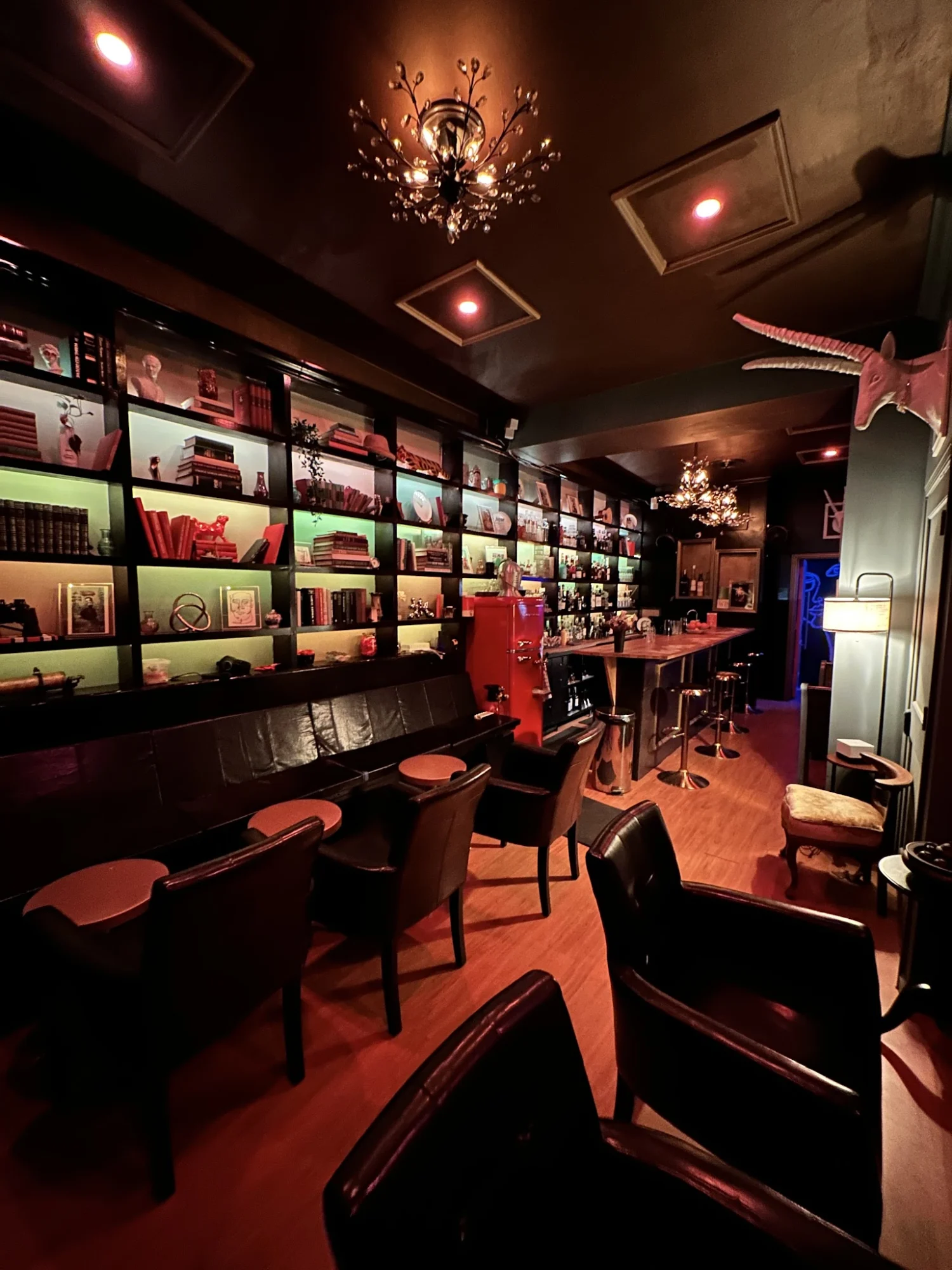 Upstairs Cocktail Bar featured image Dimly lit interior with leather seating and shelves at Upstairs Cocktail Bar, Jackson Heights.