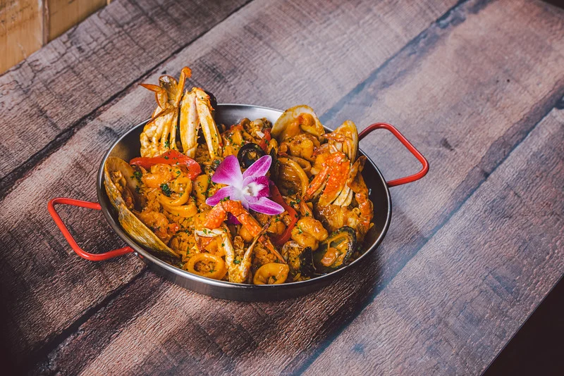 Caridad Restaurant featured image Seafood dish with assorted shellfish garnished with a pink flower at Caridad Restaurant, Fordham Bronx.